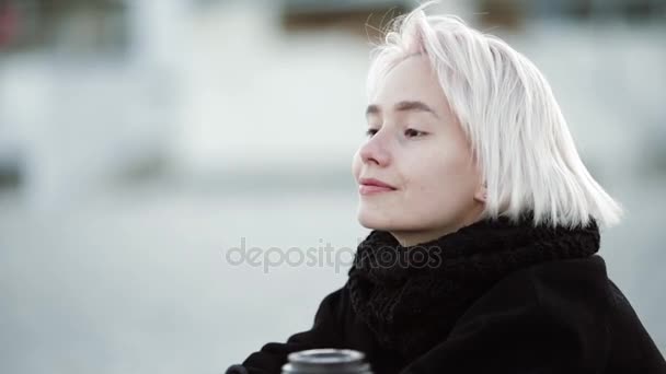 Blonde fille sur la plage boit du café Profite de la brise de la mer regarde dans la distance sourit rêves — Video