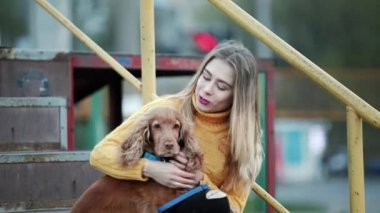 Sarışın kadın ve köpek yavru horoz İspanyol vuruş şehirde akşam köpek umurunda öpücük gülümsüyor