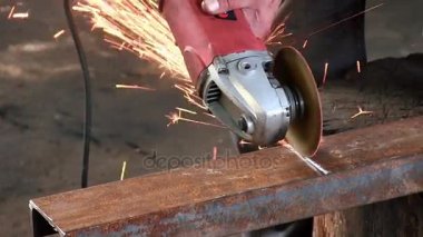 Adam bir paslı metal kiriş, dairesel bir türbini kullanarak keser. Açı değirmeni slowmotion yakın çekim ses var