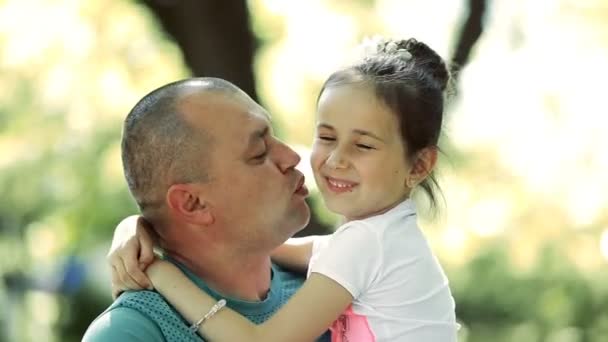 Un uomo di mezza età tiene una figlia tra le braccia, la bacia sulla guancia. Sorridono e ridono . — Video Stock