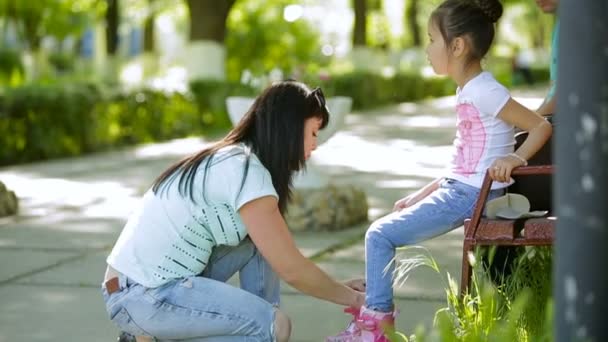 Frau mittleren Alters bringt ihrer Tochter Rollschuhe im Park bei — Stockvideo