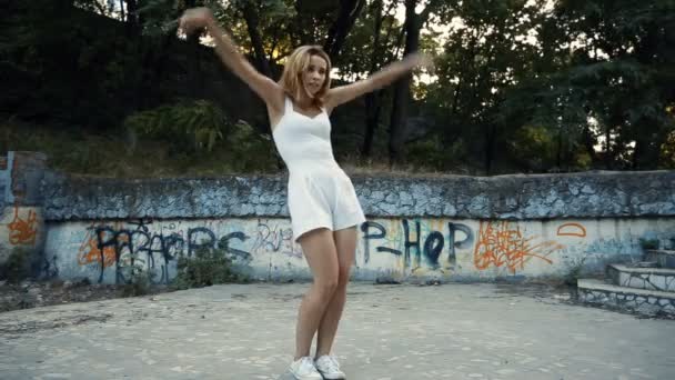 Woman dancing modern choreography in city park, outside. City ruins and graffiti. — Stock Video