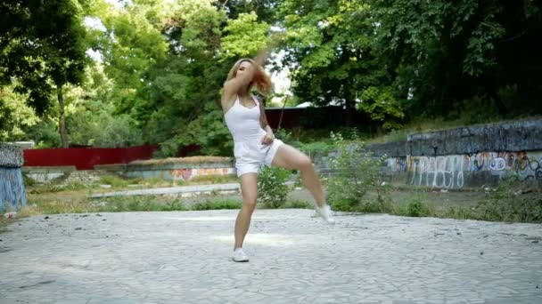 Joven mujer asiática bailando coreografía moderna en el parque de la ciudad fuera de las ruinas de la ciudad y graffiti jazz-funk — Vídeo de stock