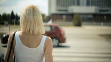 Genç sarışın kadın otomobil yol kırmızı ışık çapraz olacak geçmek için bir geçiş Back view bekler.