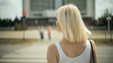 Genç sarışın kadın otomobil yol kırmızı ışık çapraz olacak geçmek için bir geçiş Back view bekler.