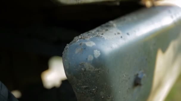 Hoja de hierba brotó de un agujero oxidado en la parte posterior de un coche blanco. Bomba — Vídeos de Stock