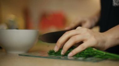 Genç kadın kız dilimleri dereotu mutfakta bir cam gemide