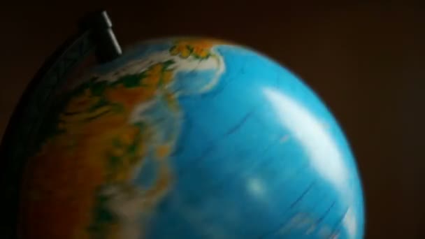 Twisting globe on a dark background, in school. It comes out of focus. — Stock Video