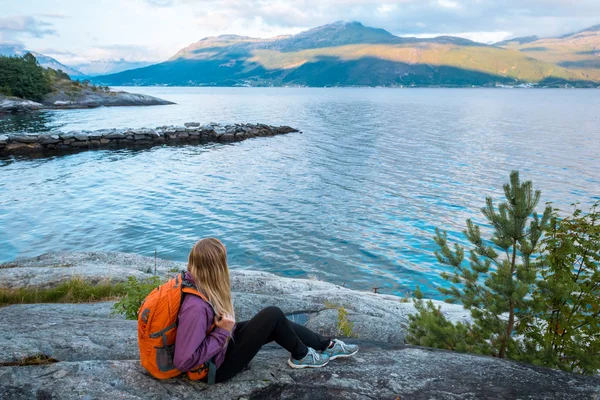 Young woman with backpack standing on fjord coast — Stock Photo, Image