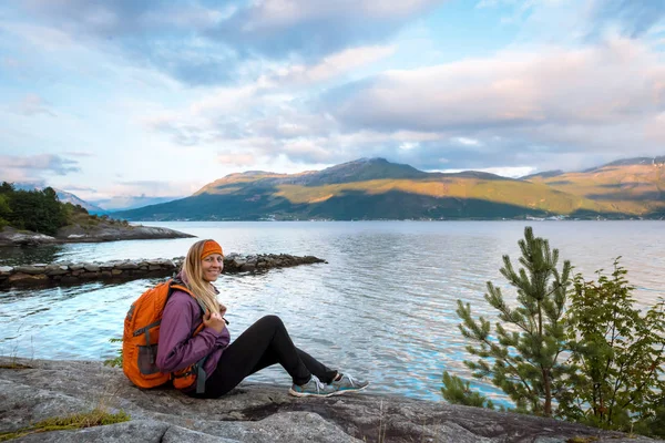 Jovem com mochila em pé na costa do fiorde — Fotografia de Stock