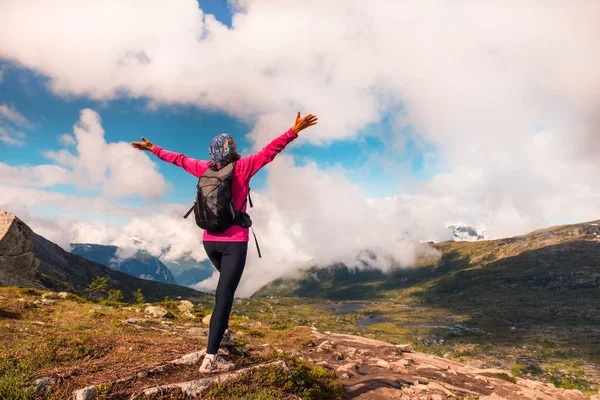 Ung kvinne med ryggsekk stående på fjordkysten – stockfoto