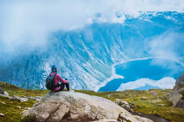Junge Frau mit Rucksack steht an der Fjordküste — Stockfoto