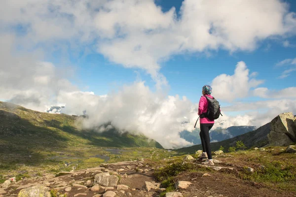 Ung kvinna med ryggsäck stående på fjorden kusten — Stockfoto