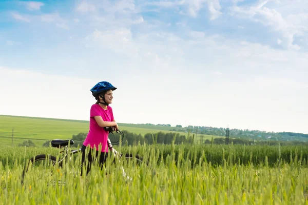 Ragazza in bicicletta nel paesaggio rurale — Foto Stock