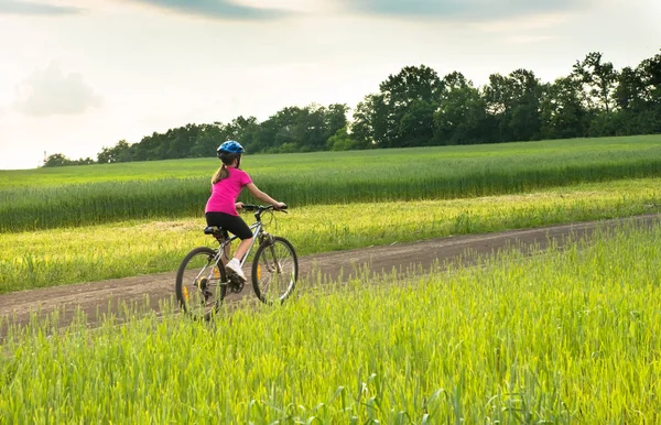 Girl on a bicycle in rural landscape — Stock Photo, Image