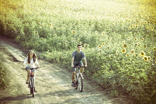 Teenie-Paar fährt Fahrrad in Sonnenblumenfeld — Stockfoto