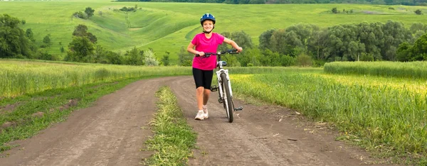 緑のフィールドで自転車とスポーティな女の子. — ストック写真