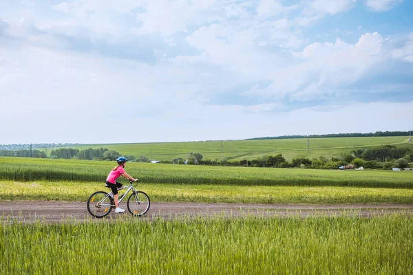Дівчина на велосипеді в сільському пейзажі — стокове фото
