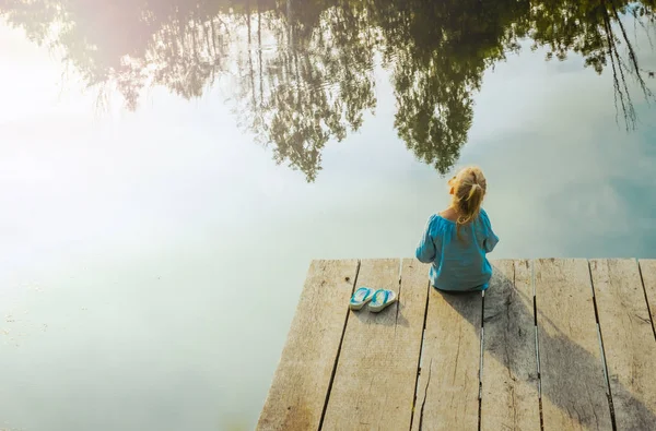 川のそばに座って孤独な小さな女の子。冒険的状況 — ストック写真