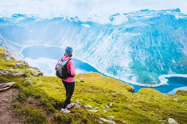 Ung kvinna med ryggsäck stående på fjorden kusten — Stockfoto