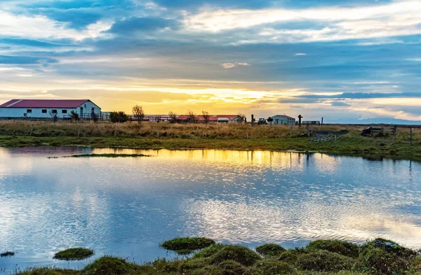 Stare gospodarstwo i małe jezioro w Islandii o wschodzie słońca. — Zdjęcie stockowe