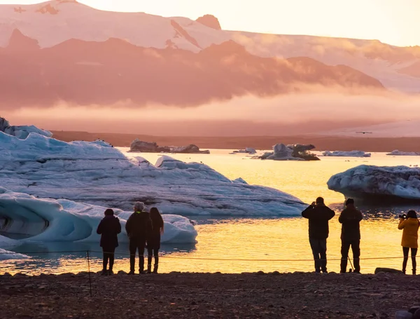 Laguna de hielo. Silueta de turistas tomando fotos de la laguna de hielo puesta del sol. Islandia — Foto de Stock