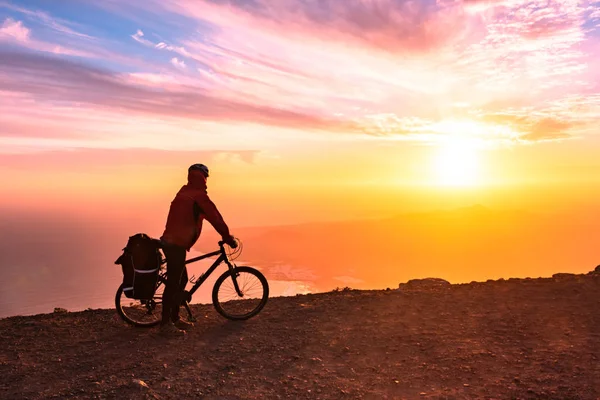 Mountain bike rider con zaino viaggia su sfondo alba — Foto Stock