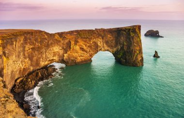 Natural lava arch in the sea. Cape Dyrholaey, coast of Iceland.