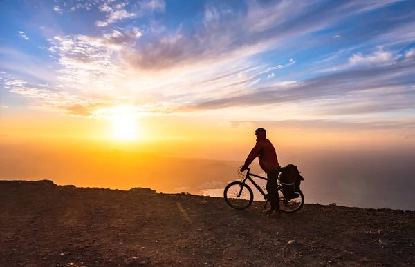 Mountain bicycle rider with backpack travels over sunrise background — Stock Photo, Image