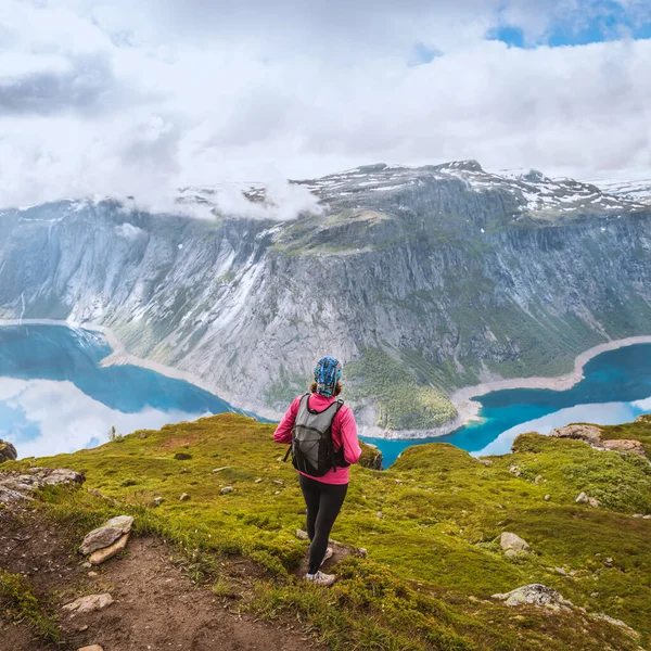 Ung kvinne med ryggsekk stående på fjordkysten – stockfoto