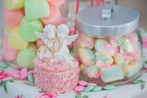 Obrączki ślubne w Szkatułka z aniołami na tle ozdobny szklanych słoików z candy marshmallows — Zdjęcie stockowe