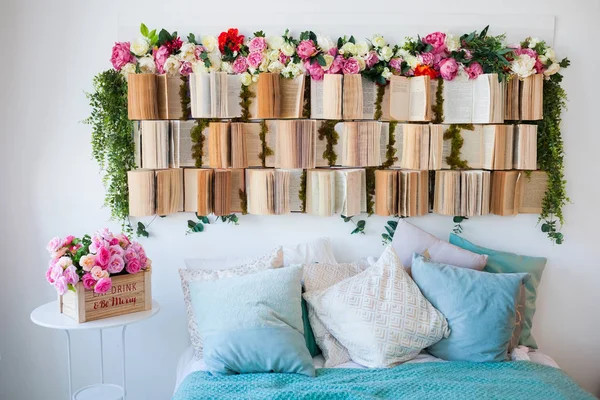 Den ovanliga designen av sovrummet. Sänggaveln är dekorerad med böcker och blommor. — Stockfoto