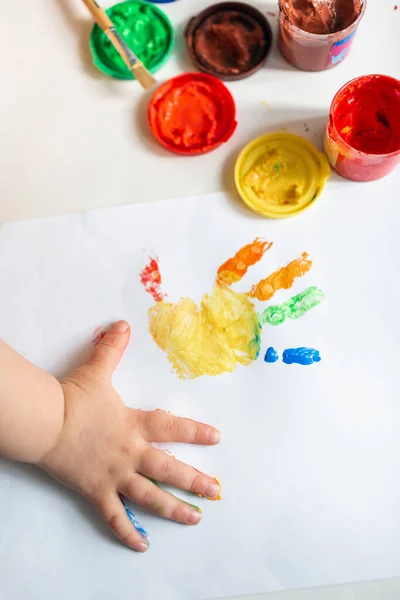 Close up of colored hand print on white background. Ideas for drawing with finger paints. Finger painting for kids. Little girl painting by finger hand paint color. Children development concept.