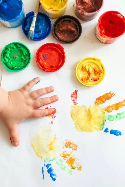 Close up of colored hand print on white background. Ideas for drawing with finger paints. Finger painting for kids. Little girl painting by finger hand paint color. Children development concept.