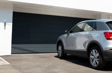 Araba garajda büyük garaj kapısı ile girmek için bekleyen modern ev önünde