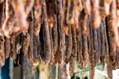 Hanging sausages in smokehouse for sale at the winter Christmas market clipart