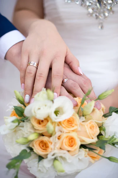 Ruce a prsteny na svatební kytici — Stock fotografie