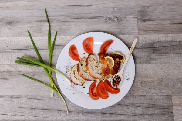 Gebackene Hühnerbrötchen mit Tomate und Zitrone und Gewürzen auf weißem Teller auf weißem Holztisch — Stockfoto