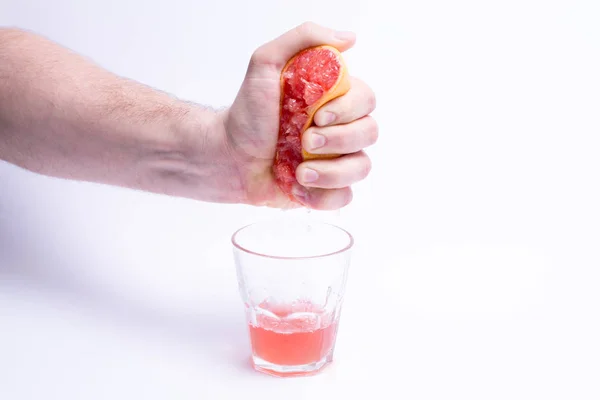 Mão masculina agarrando toranja, suco de toranja no fundo branco — Fotografia de Stock