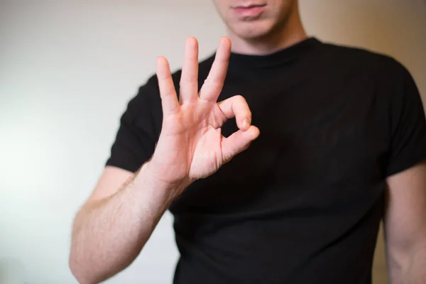 Homem jovem sério mostrando okey gesto isolado no fundo da parede cinza — Fotografia de Stock