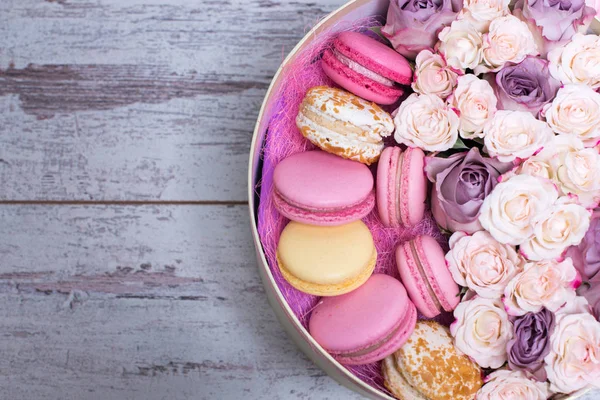 Box mit frischen Blumen und Makronen auf hölzernem Hintergrund — Stockfoto