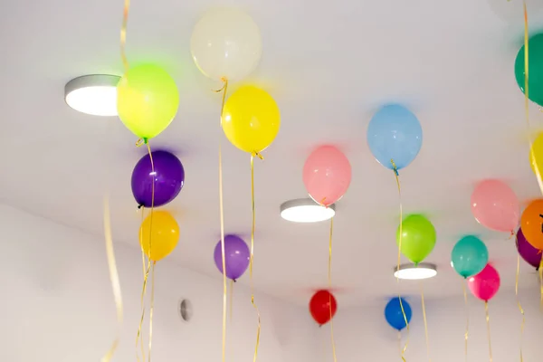 Globos de colores cuelgan bajo el techo blanco . — Foto de Stock