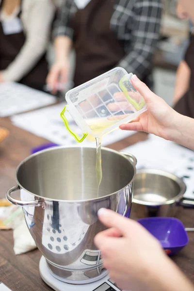 Cocinar vertiendo aceite vegetal a la sartén que se encuentra en las escamas . — Foto de Stock