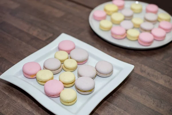 Renkli Fransızca veya İtalyanca macarons yığını beyaz tabakta kopya alanı için arka plan ile ahşap masa koymak. — Stok fotoğraf