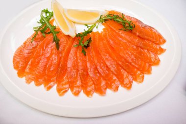 plaka withlemon beyaz zemin üzerine kırmızı dilimlenmiş balık.