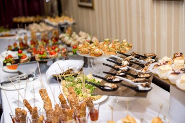 Burgerler, soğuk atıştırmalıklar, et ve salatalarla dolu açık büfe masası.