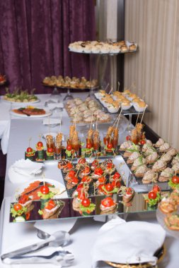 Burgerler, soğuk atıştırmalıklar, et ve salatalarla dolu açık büfe masası.