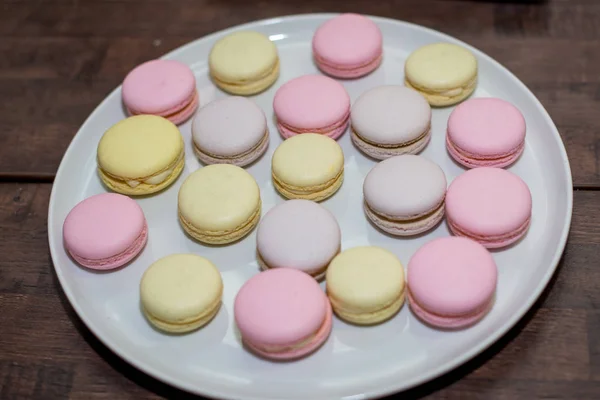 Farbenfrohe französische oder italienische Macarons stapeln sich auf weißem Teller auf Holztisch mit Kopierraum für Hintergrund. — Stockfoto