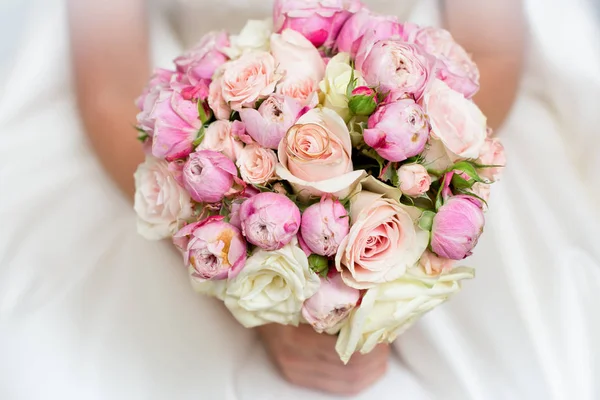 Un bouquet de roses et de pivoines dans les mains de la mariée. Gros plan. Sur un fond flou — Photo