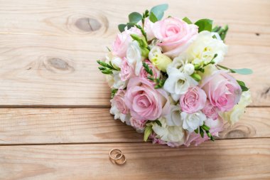 İki altın alyans ve güzel düğün kahverengi ahşap masa üzerinde vardır